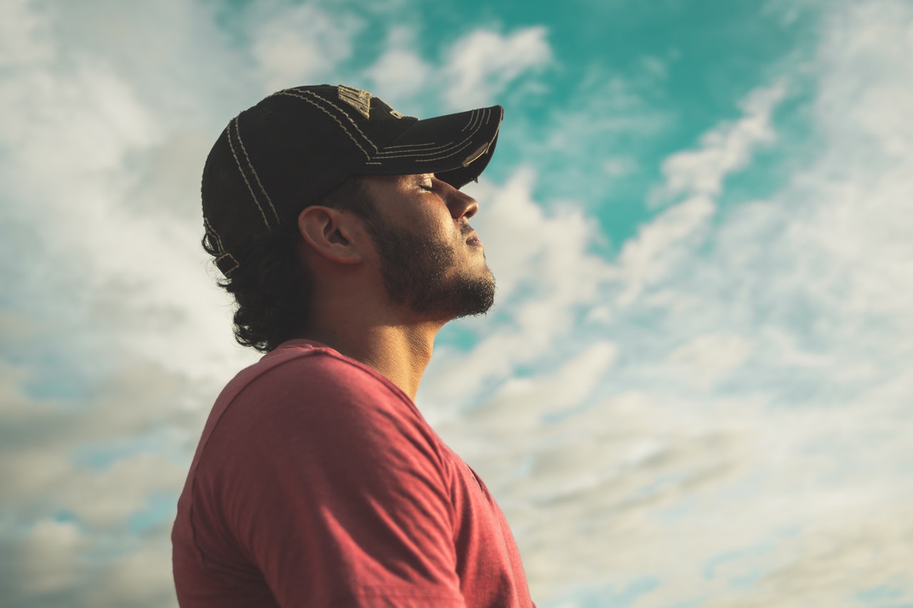 man-wearing-black-cap-with-eyes-closed-under-cloudy-sky-810775.jpg